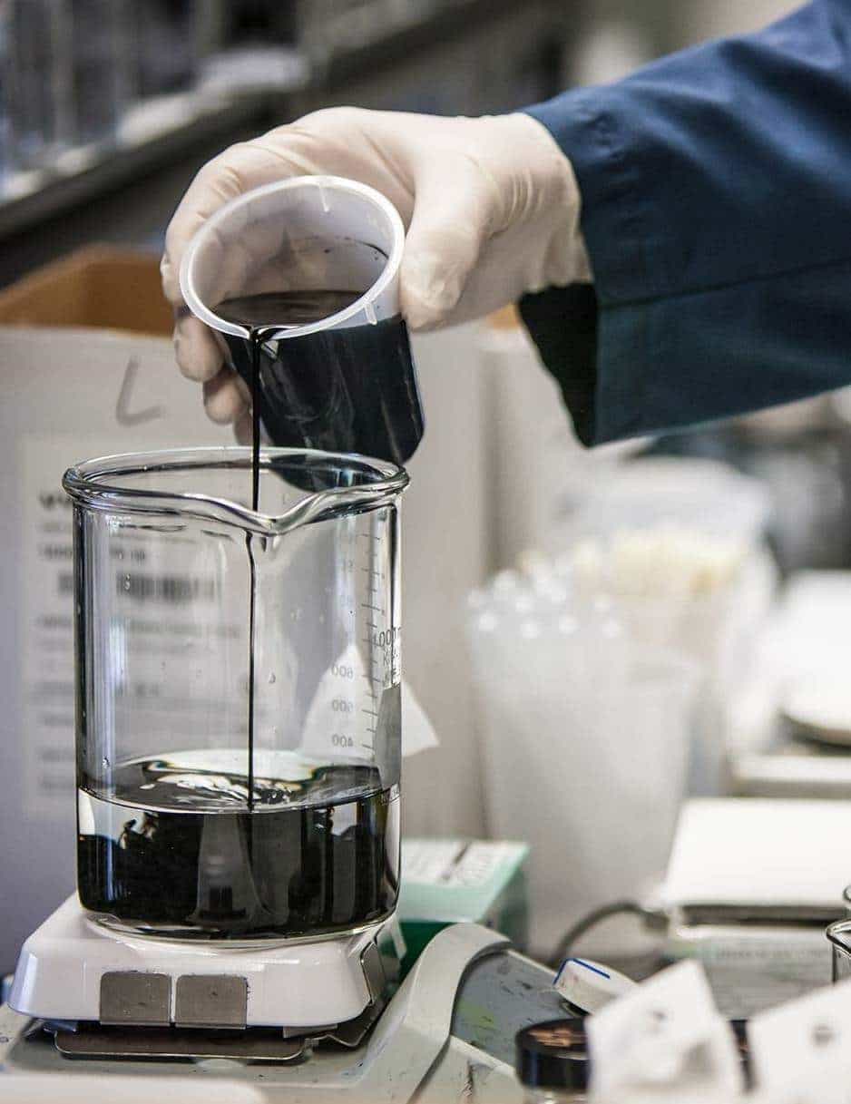 Chemist pouring ink into a beaker for a custom formulation