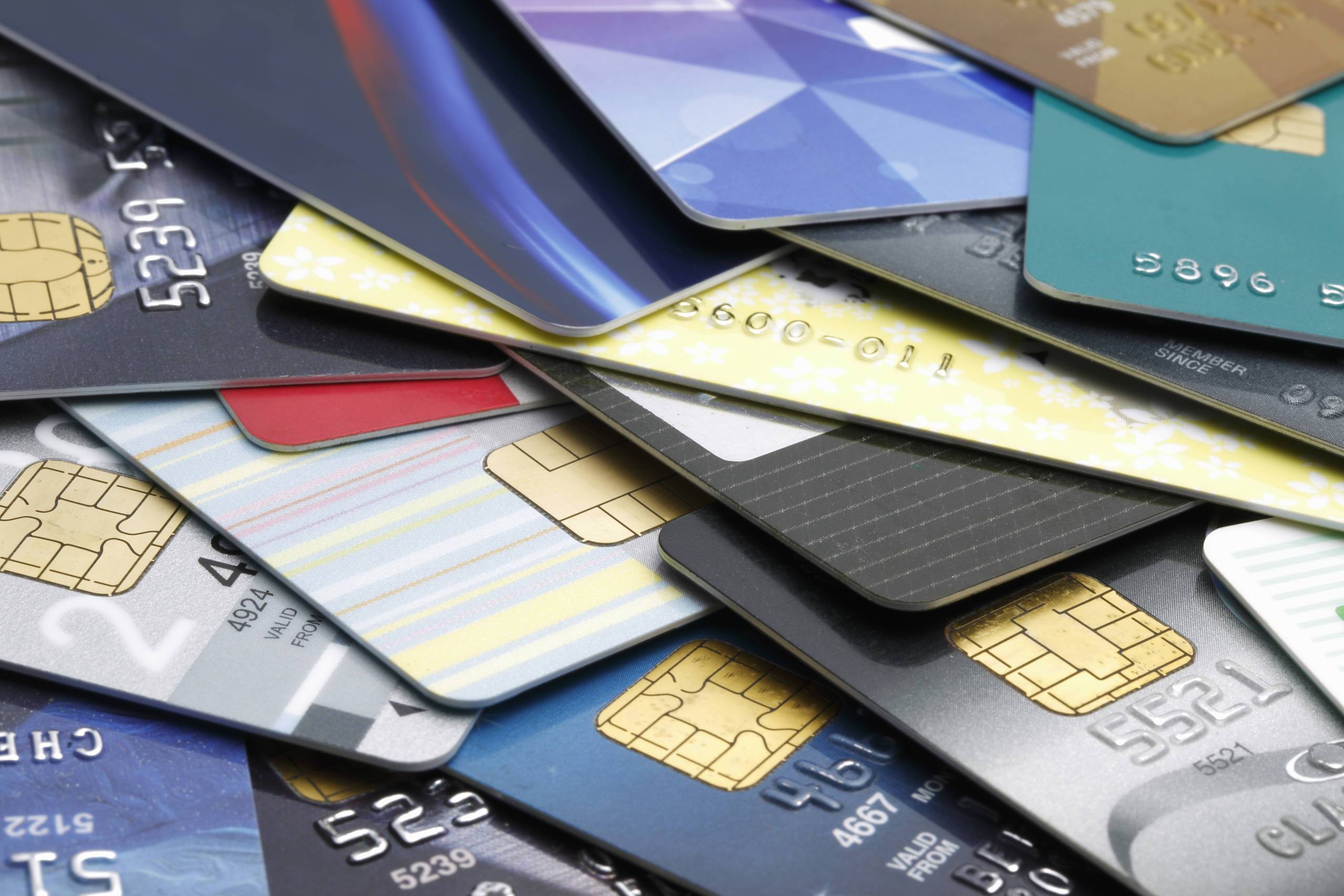 A pile of various credit and plastic cards with embedded chips, showcasing diverse designs and colors.